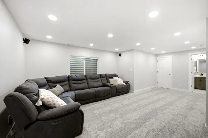 Recessed lighting, light gray wall paint, patterned gray carpeting, white trim, and a white three-panel door