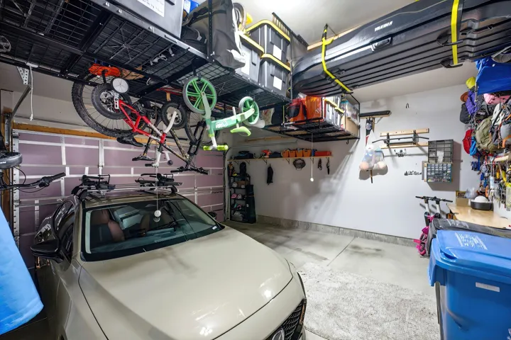 Garage featuring concrete flooring, overhead storage racks, wall-mounted shelving, and a built-in workbench