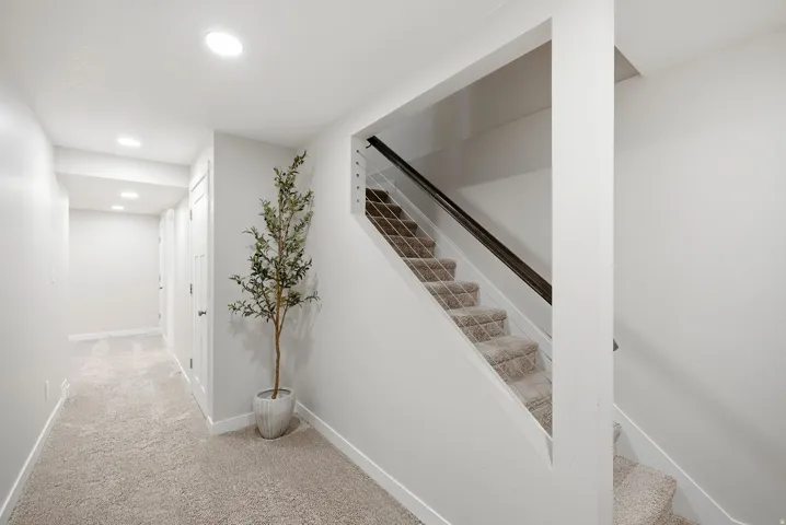 Hallway featuring recessed lighting, light-toned carpeting, and white doors