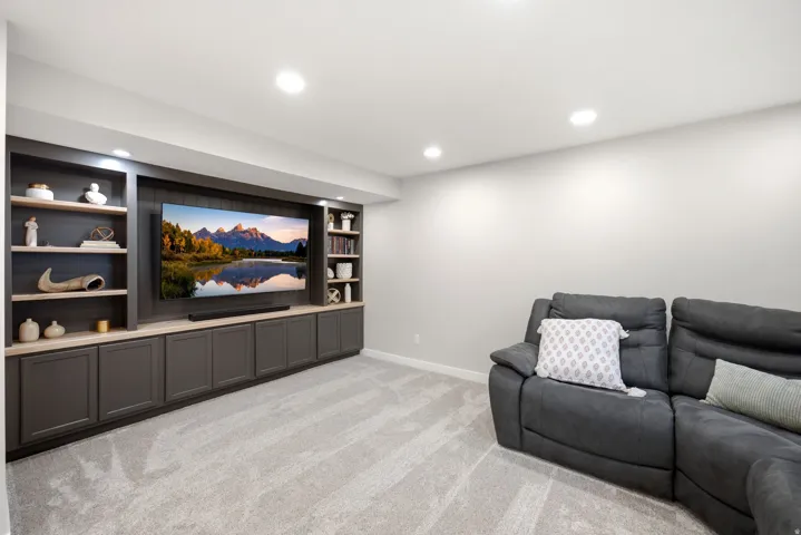 Custom built-in entertainment center featuring dark cabinetry, open shelving, and integrated lighting