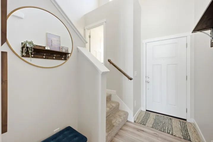 Entryway featuring a paneled door, wood-finish flooring, and a staircase with carpeted treads and a wooden handrail