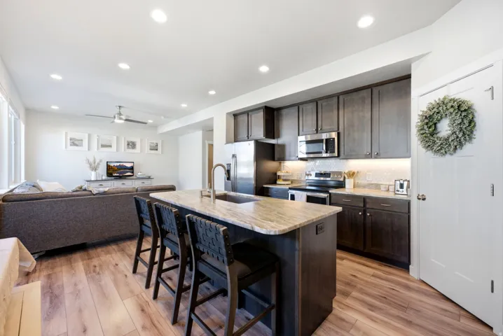 Open-concept kitchen and living area featuring wood-finish flooring, recessed lighting, and a ceiling fan
