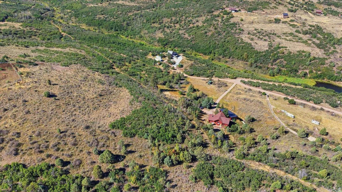Expansive rural landscape featuring multiple structures, abundant natural foliage, and visible roadways