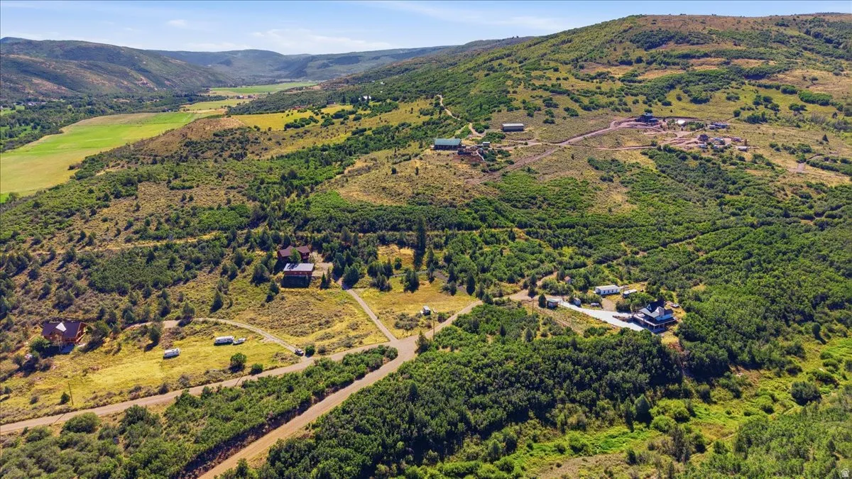 Expansive rural landscape featuring multiple structures, rolling hills, and abundant natural foliage