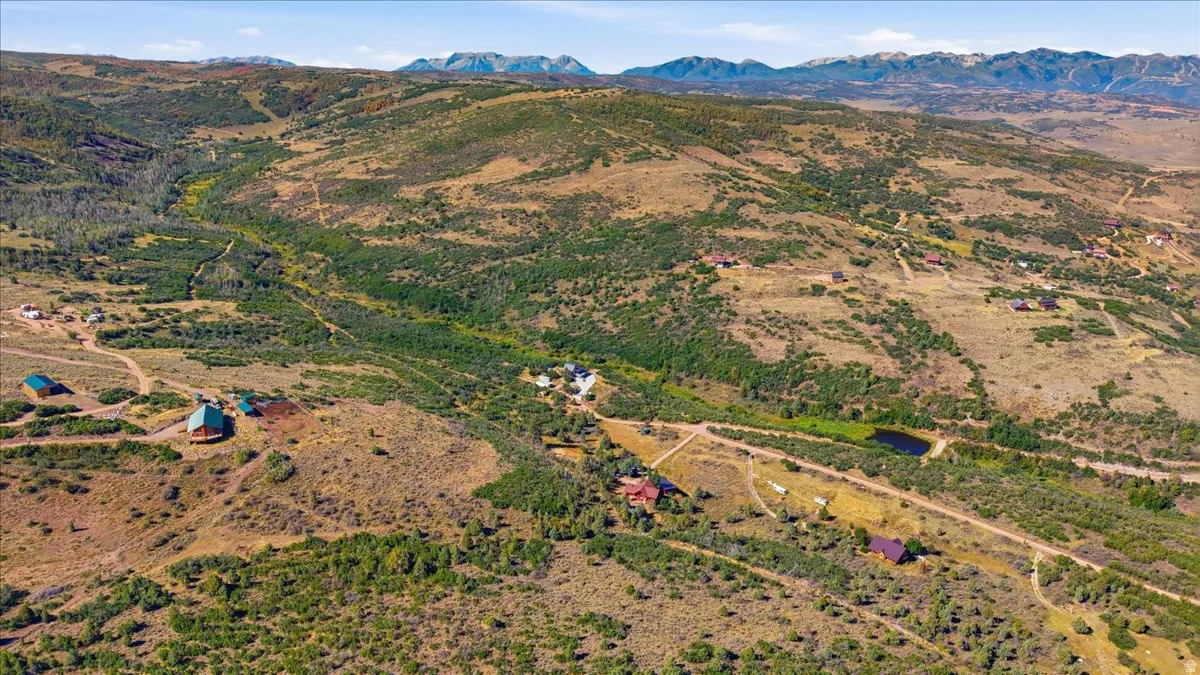Expansive rural landscape featuring scattered residential structures, natural waterways, and distant mountain ranges