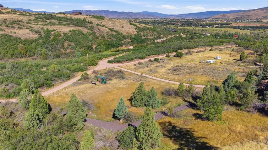 Expansive natural landscape with varied terrain, featuring extensive tree coverage and visible dirt roads