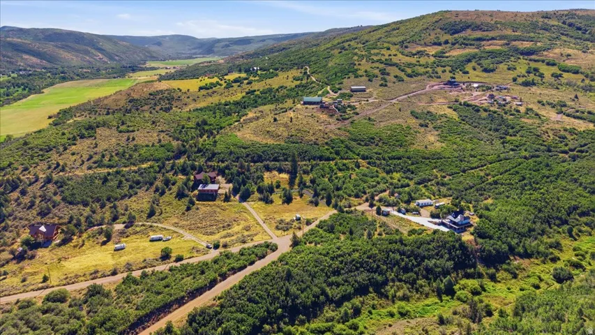 Expansive rural landscape featuring multiple structures, rolling hills, and abundant natural foliage
