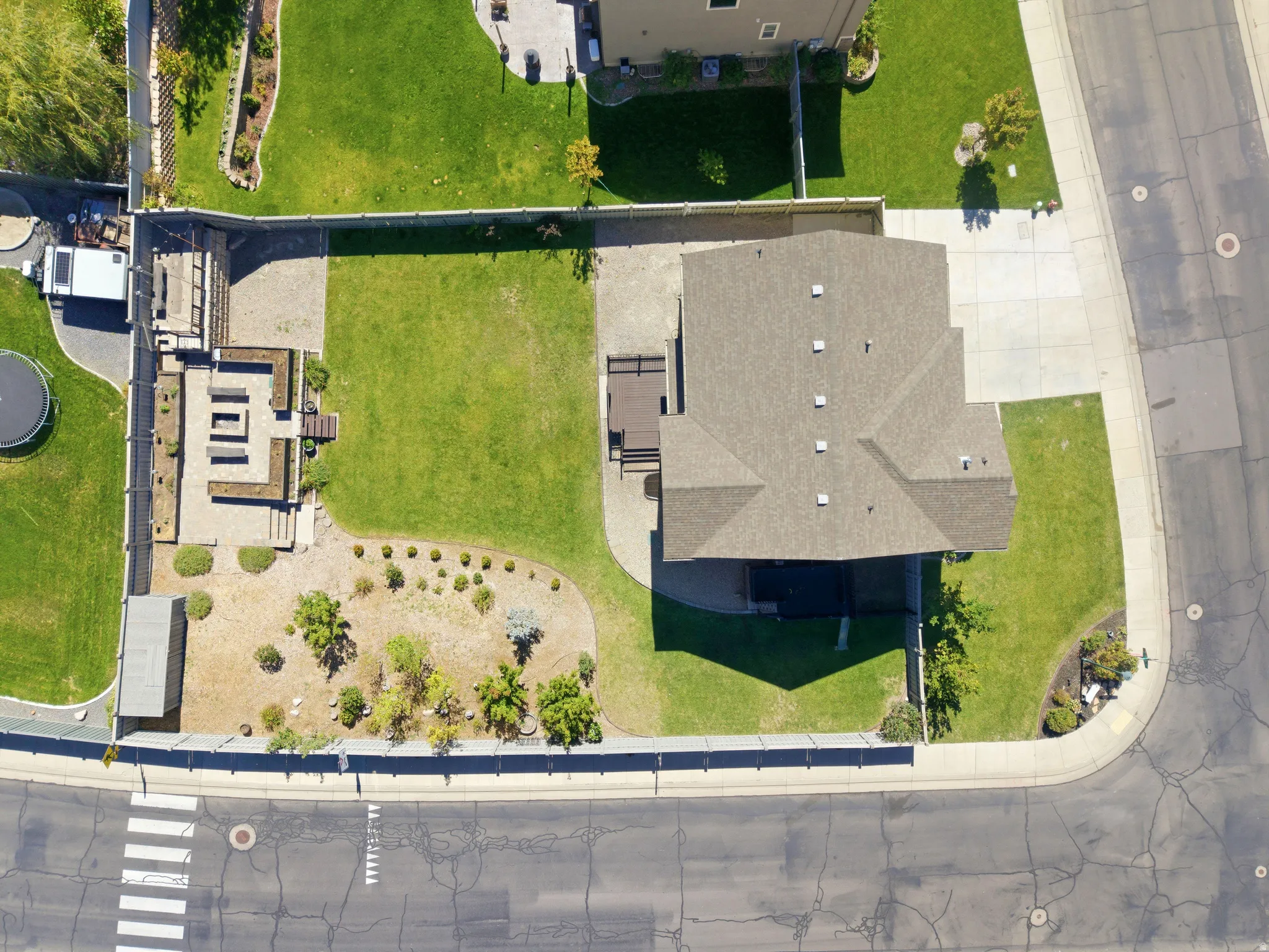 Expansive property featuring a multi-level outdoor living area, a large grassy lawn, concrete driveway, and established landscaping