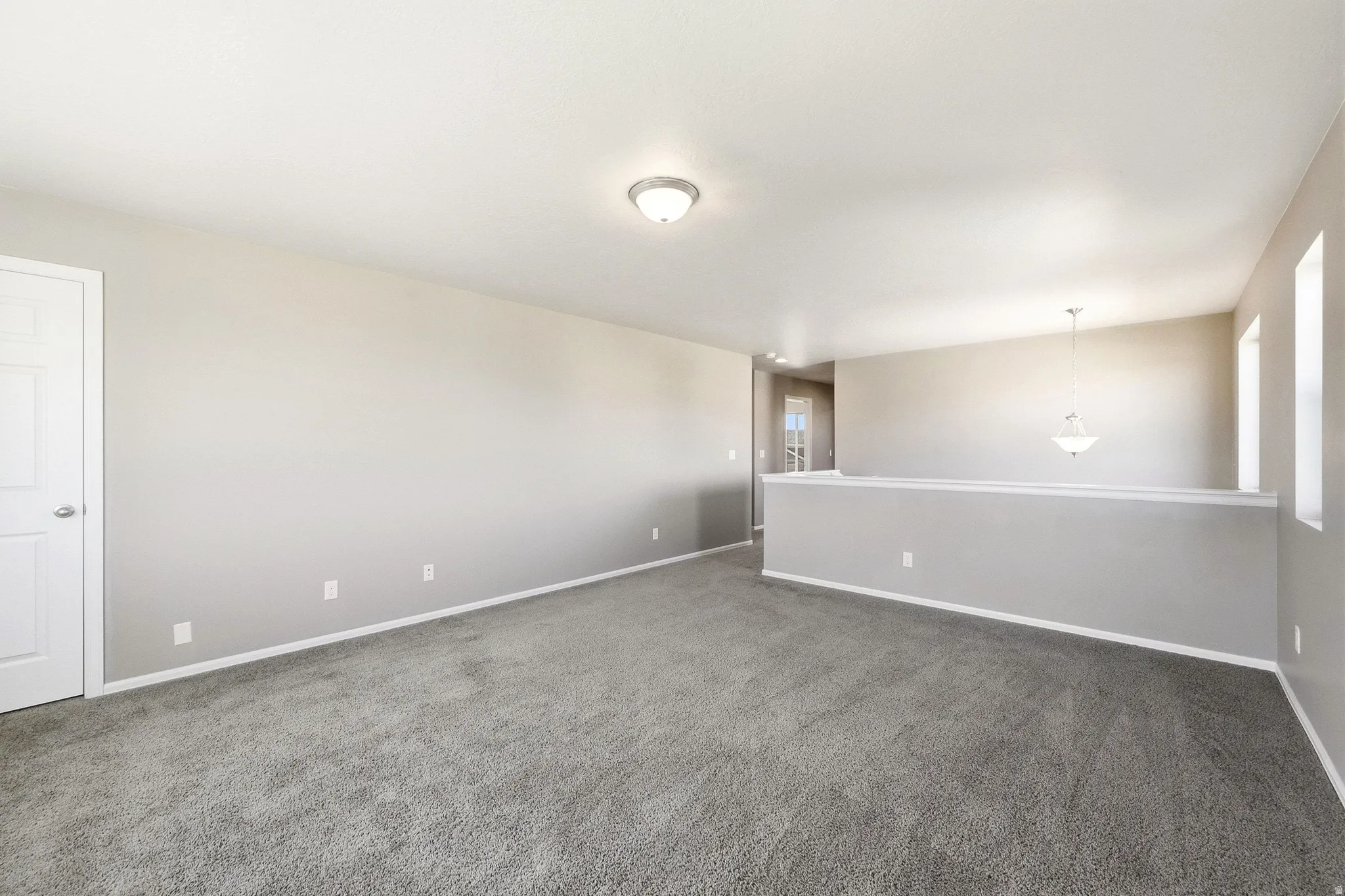 Spacious carpeted area with neutral wall tones and multiple windows