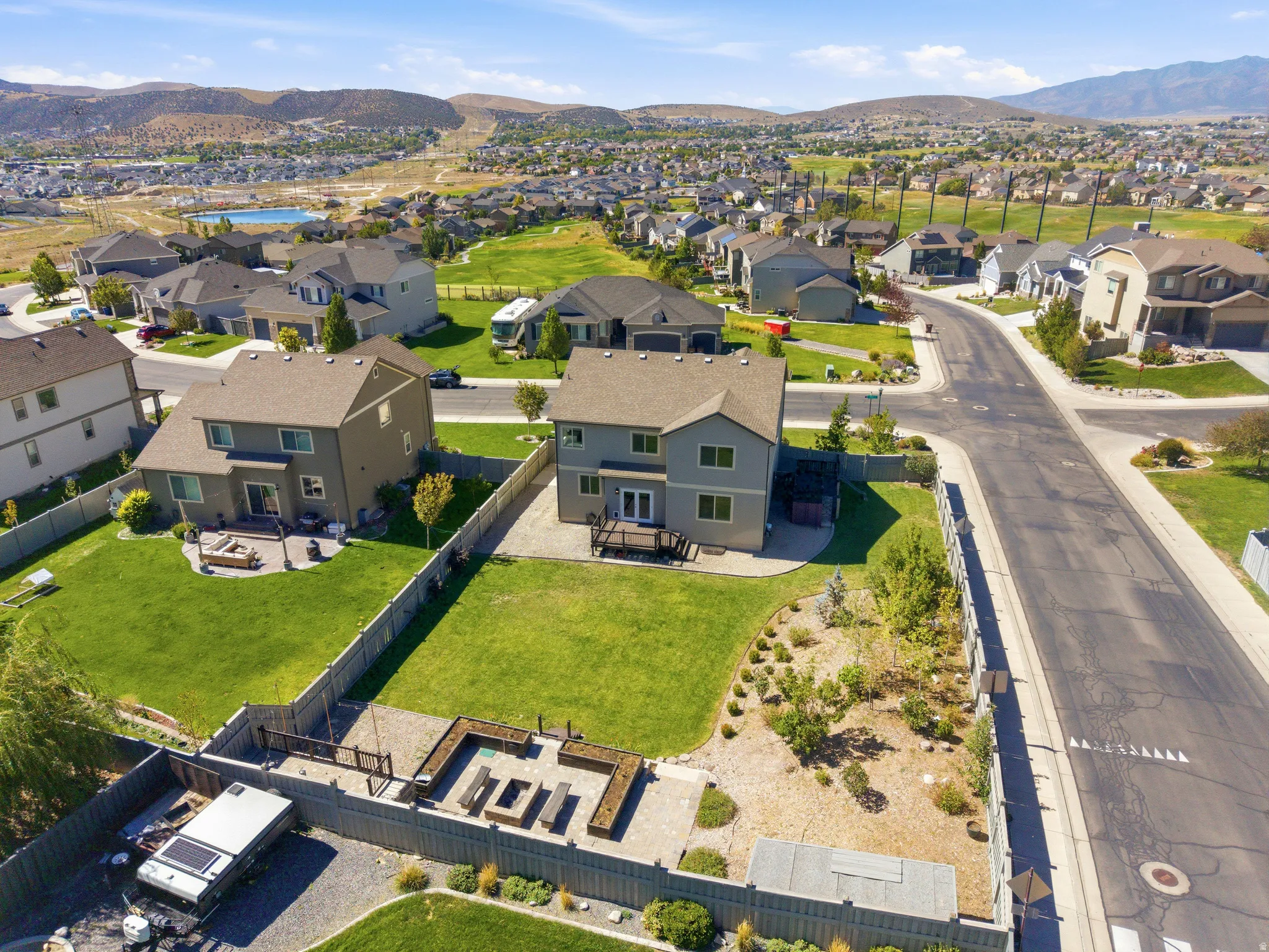 Expansive backyard with a large lawn, wood deck, and paved patio area