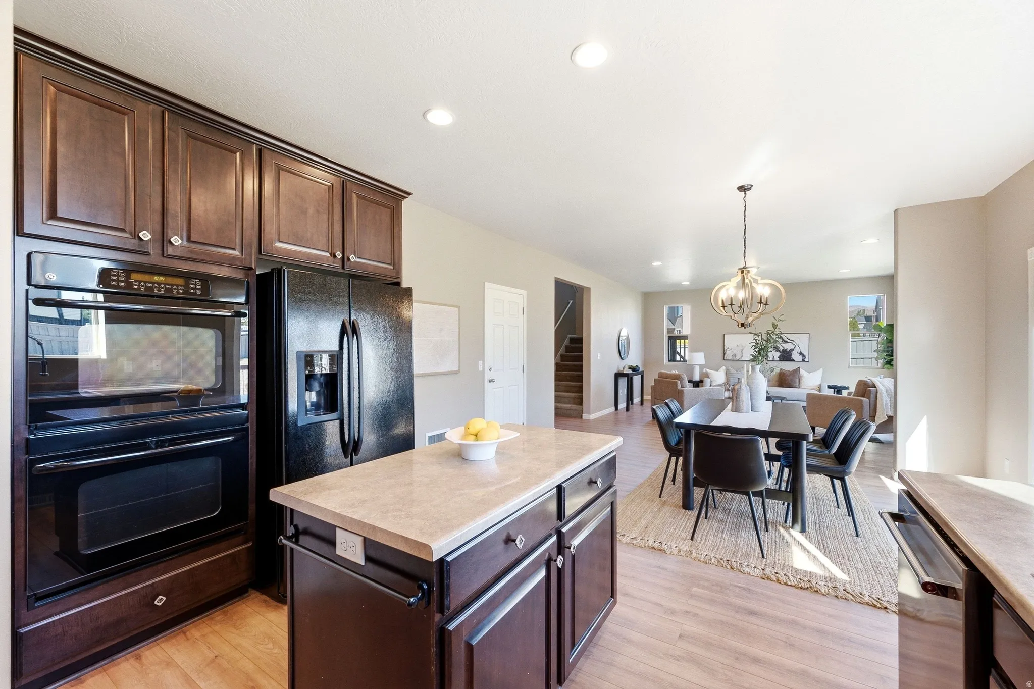 Kitchen featuring dark wood cabinetry, black built-in double ovens, and a kitchen island with integrated storage