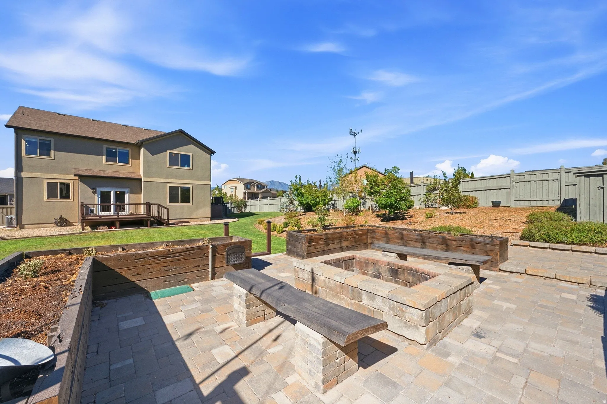 Paver patio with a built-in fire pit, integrated wood benches, and wood-sided raised garden beds