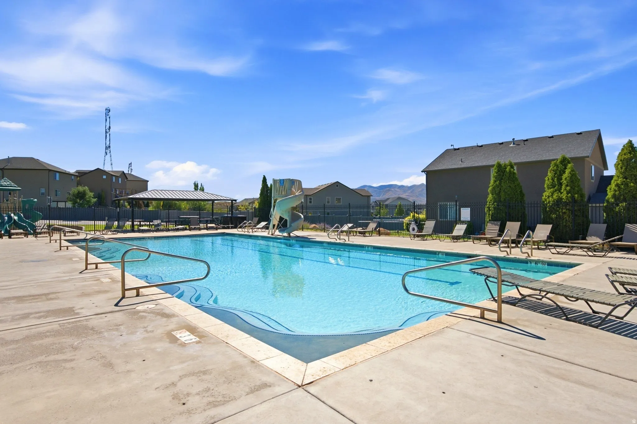 Community swimming pool featuring concrete decking, a covered pavilion, and a waterslide