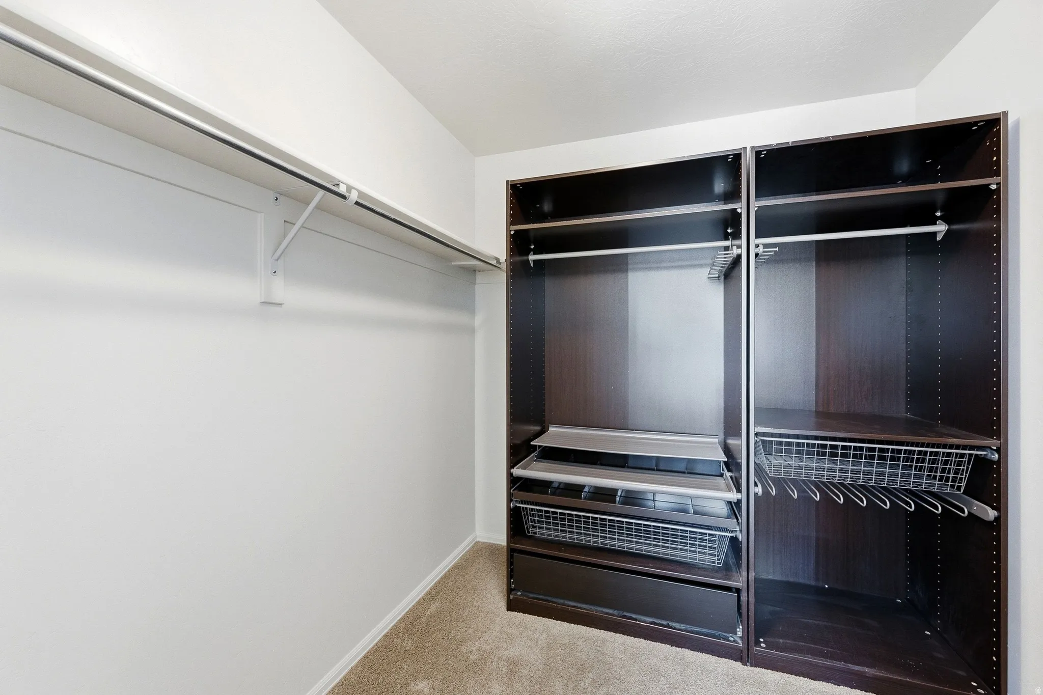 Custom closet system with dark wood-finish cabinetry, integrated metal drawers, and shelving