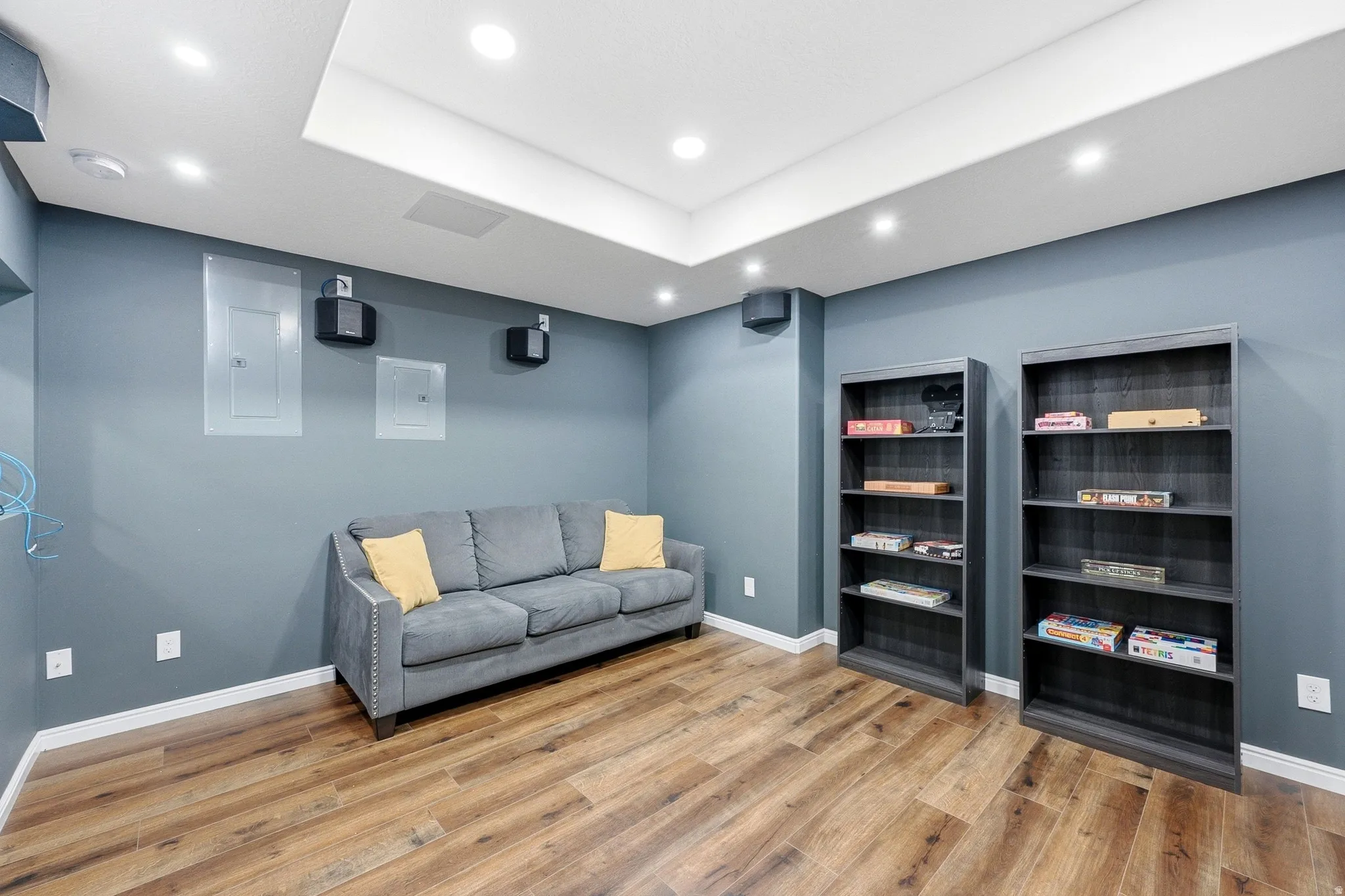 Recessed lighting illuminates the wood-finish flooring and neutral wall color
