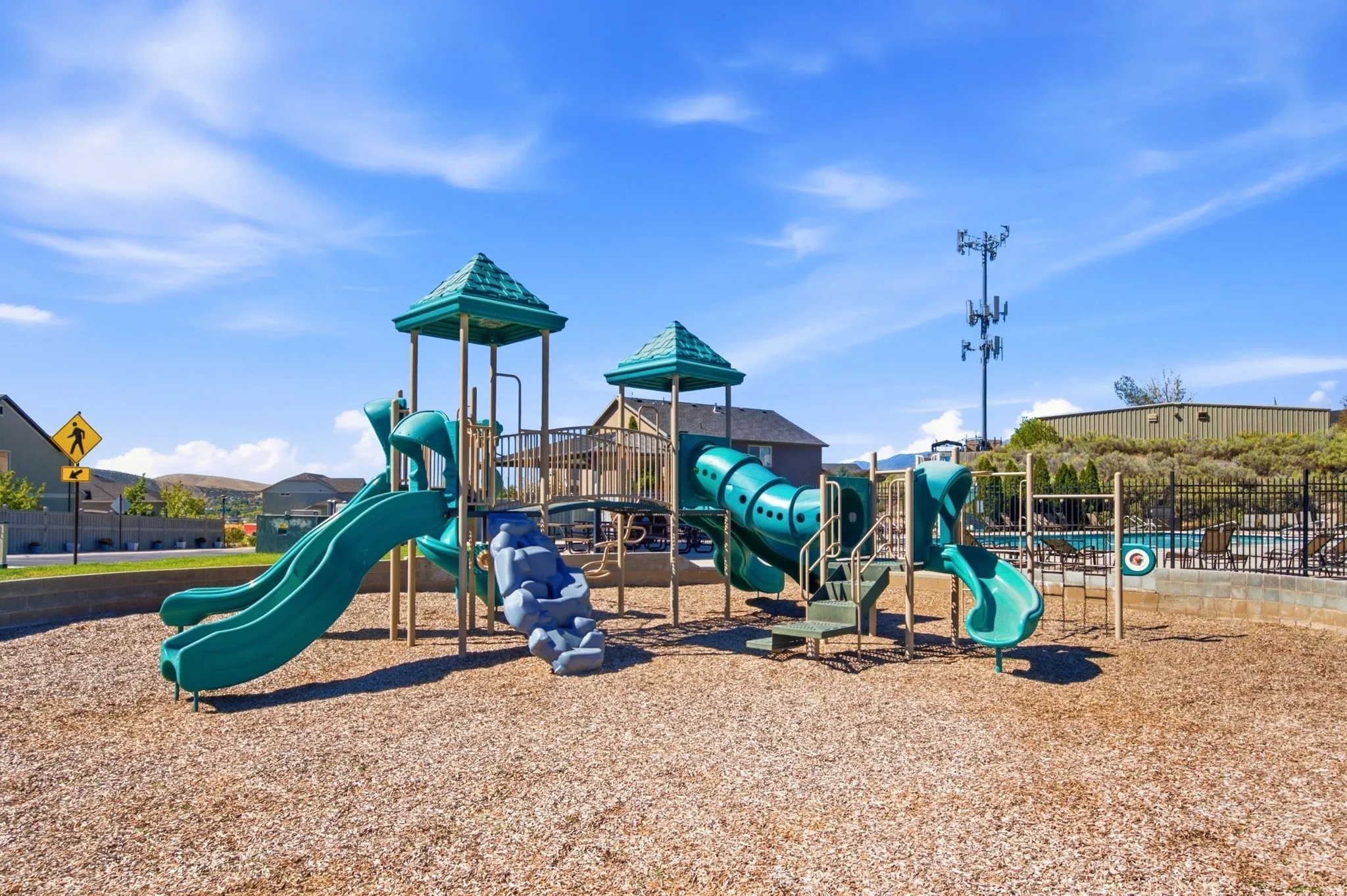 Community playground with multiple slides, climbing features, and a wood chip surface