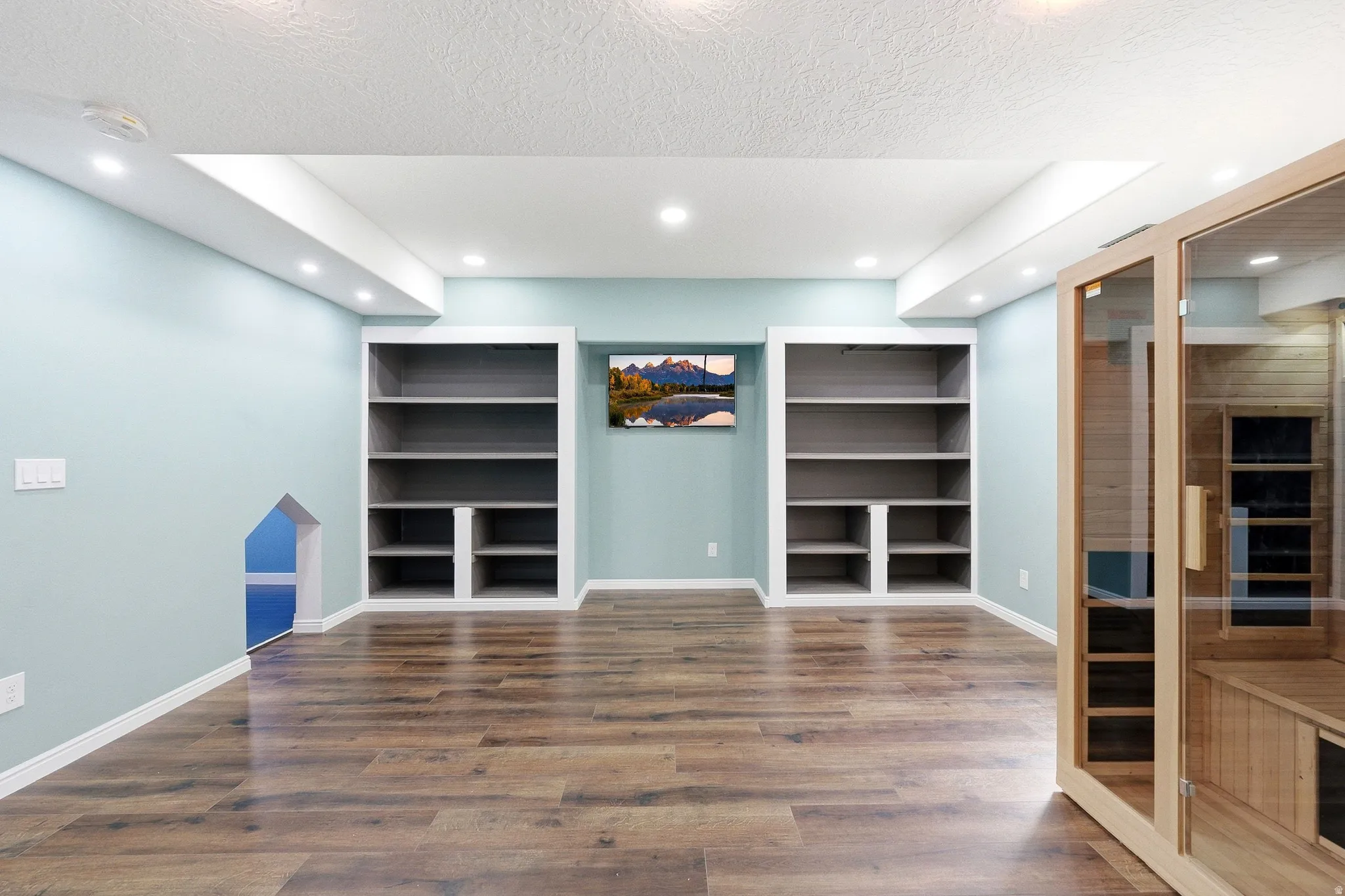 Wood-finish flooring, recessed lighting, built-in shelving, and a built-in sauna