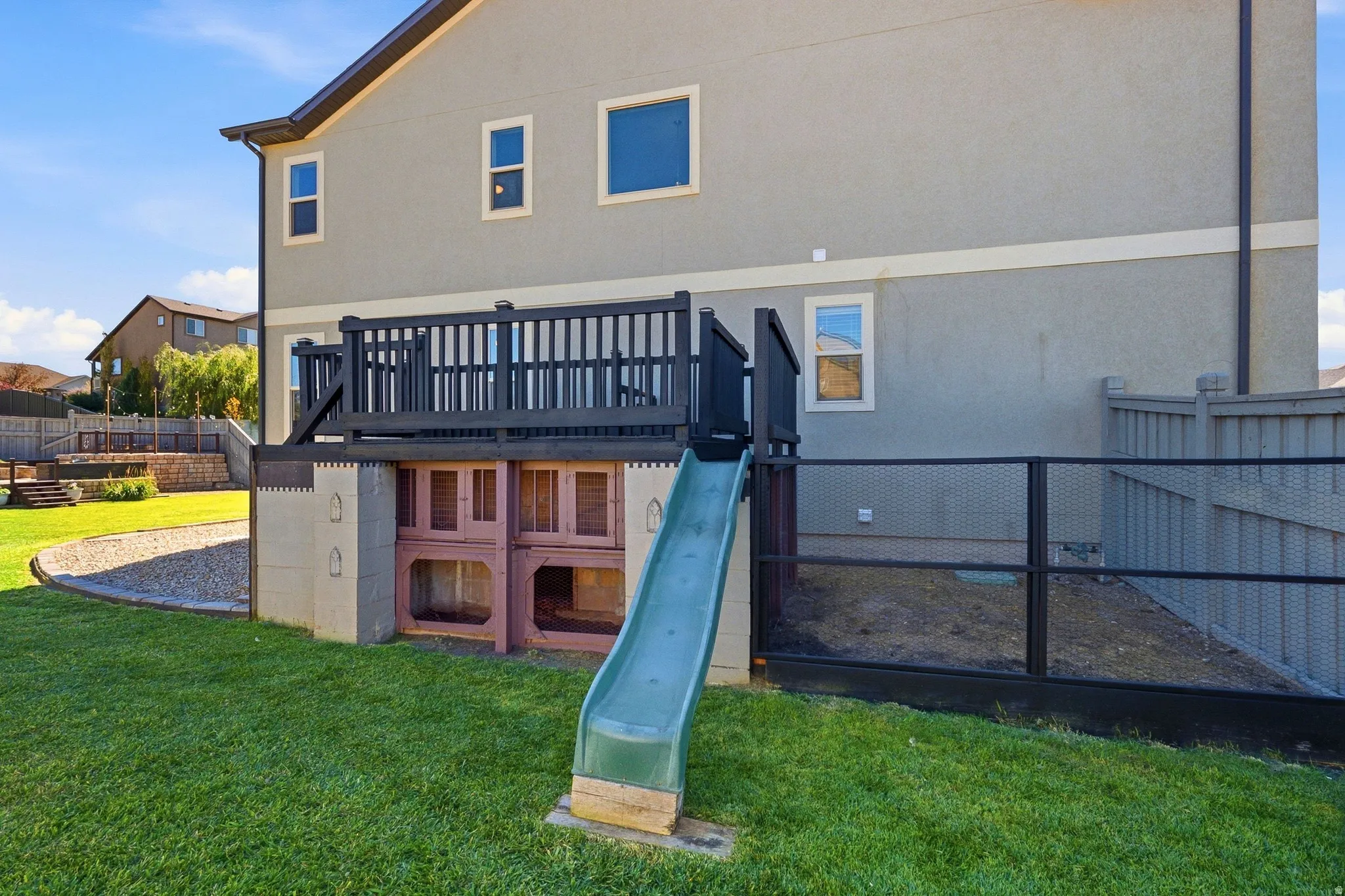 Rear exterior with a raised deck, wood balusters, and a stucco finish