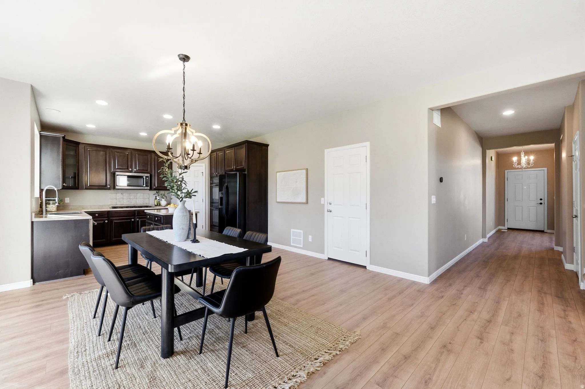 Open-concept dining area with wood-finish flooring, a contemporary chandelier, and recessed lighting