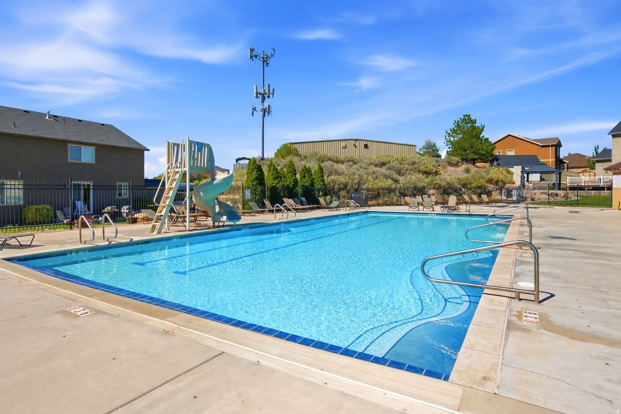 Outdoor swimming pool with integrated slide and deck access