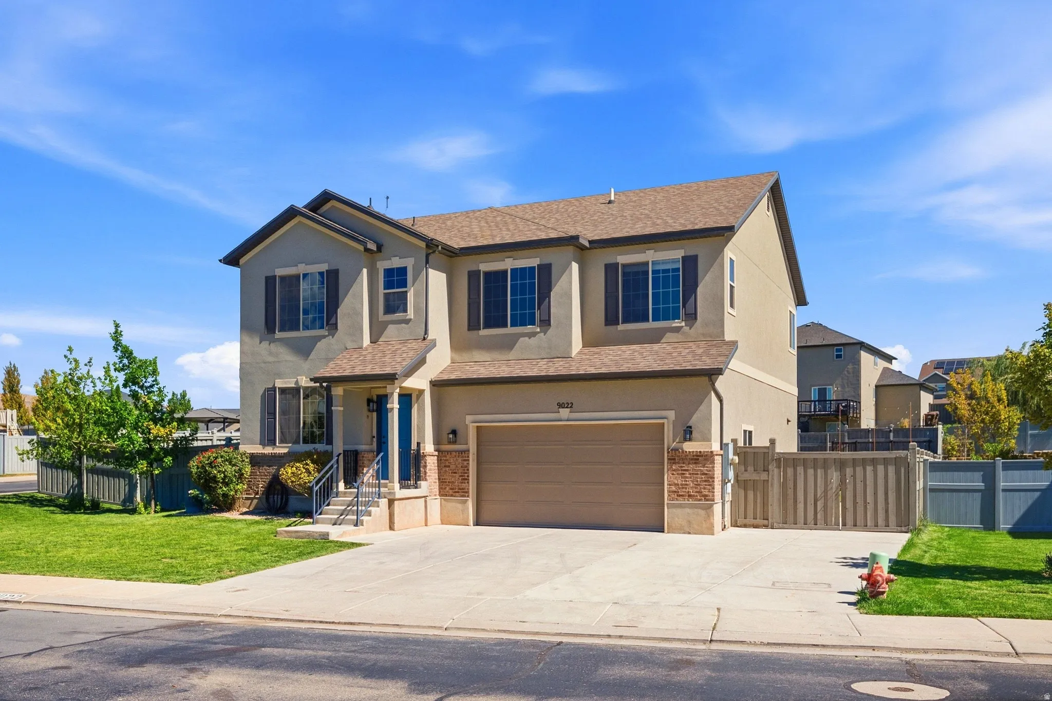 Two-story stucco exterior with stone accents, attached garage, covered entryway, and a concrete driveway