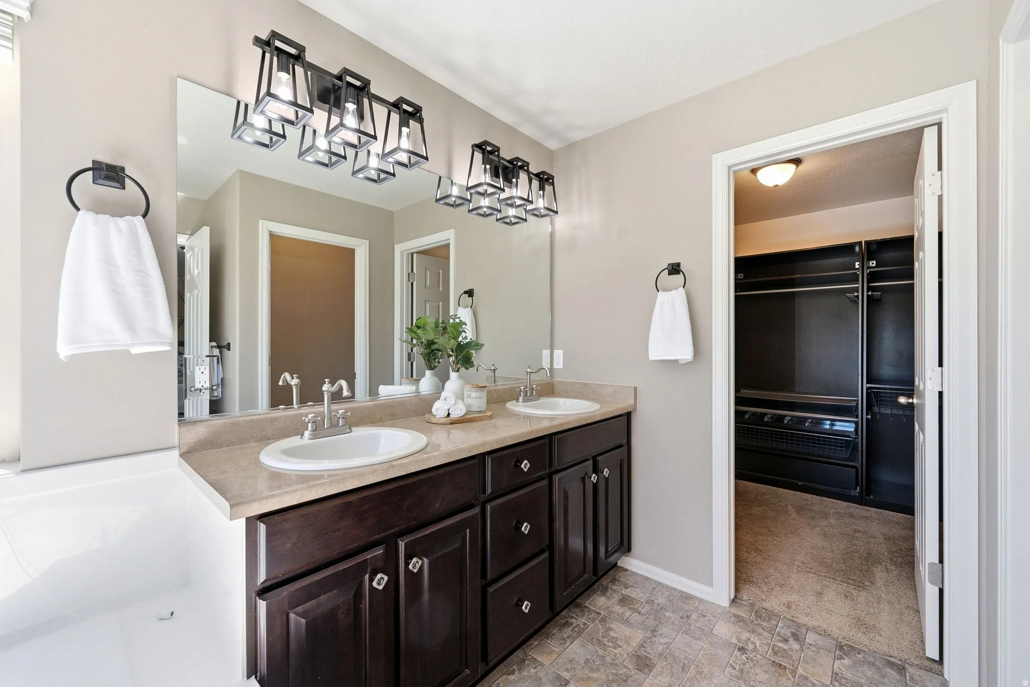 Dual vanity with dark wood-finish cabinetry, light-toned countertop, and rectangular mirrors