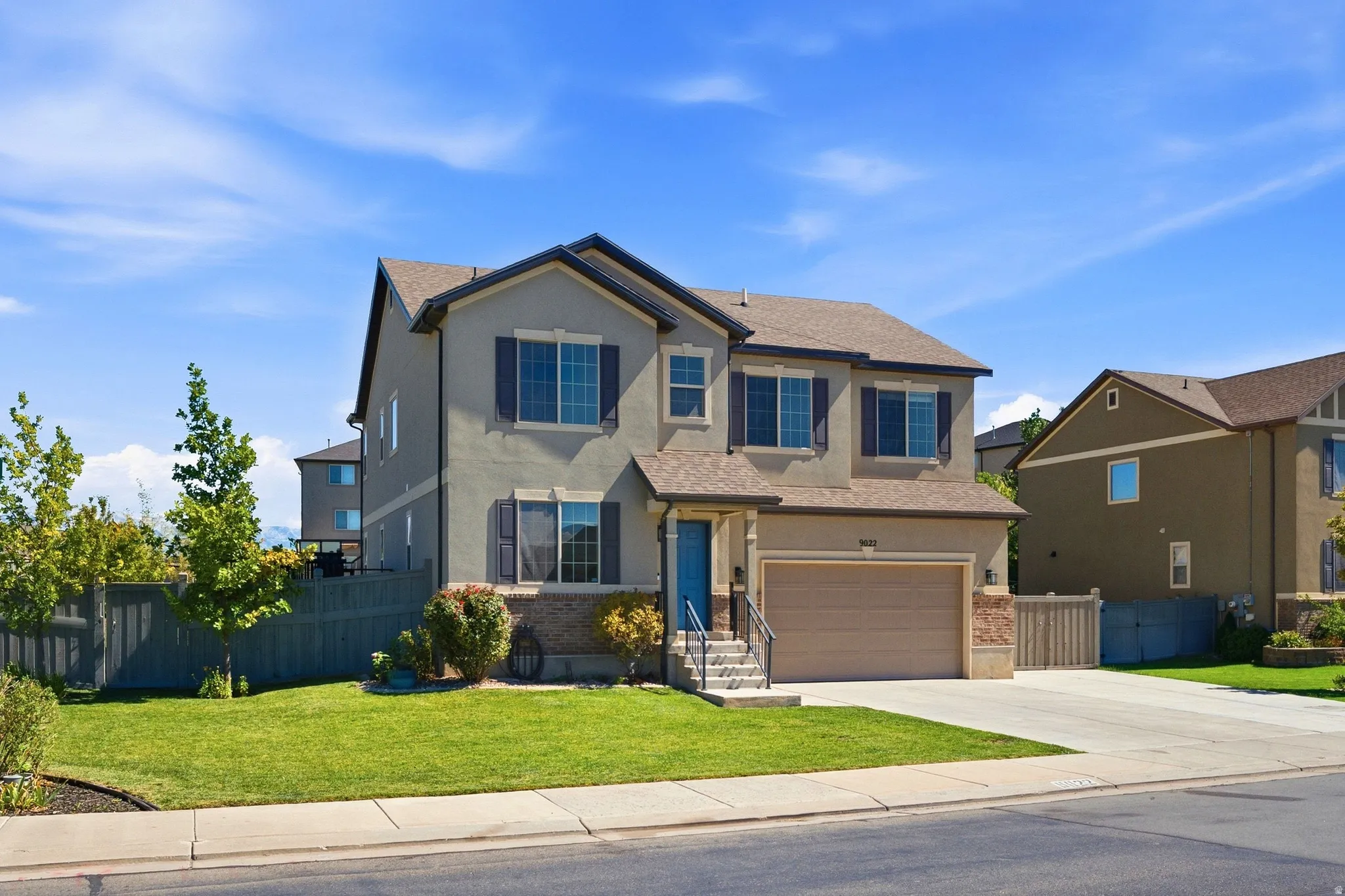Two-story residence featuring a stucco exterior, attached garage, concrete driveway, and front lawn