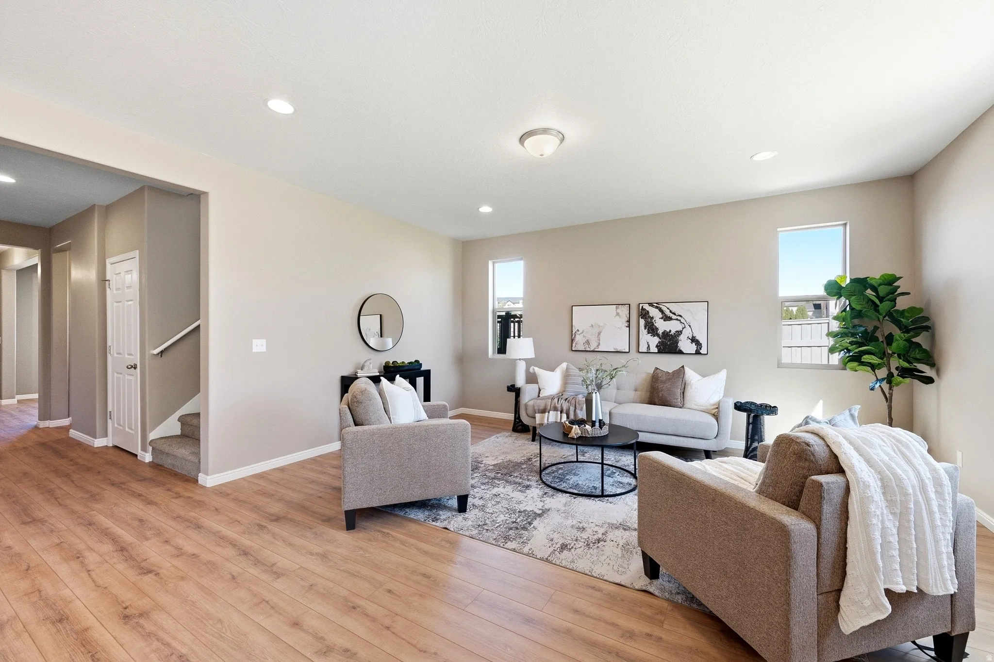 Spacious living area featuring wood-finish flooring, recessed lighting, and multiple windows