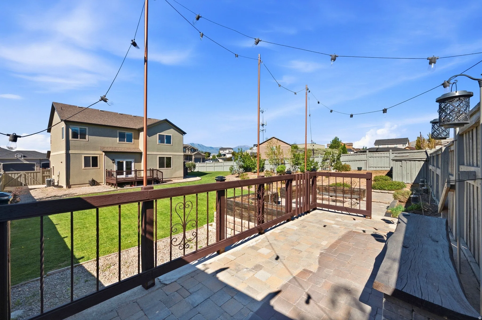 Paver patio with a built-in wooden bench and string lighting