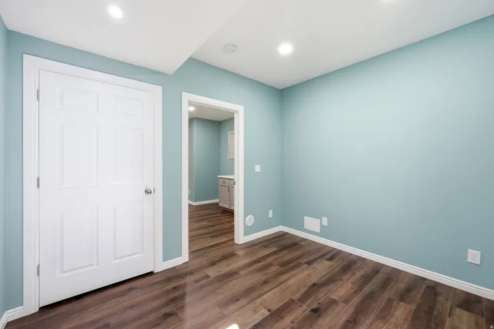Wood-finish flooring, recessed ceiling lighting, light blue wall paint, white trim, and white paneled doors
