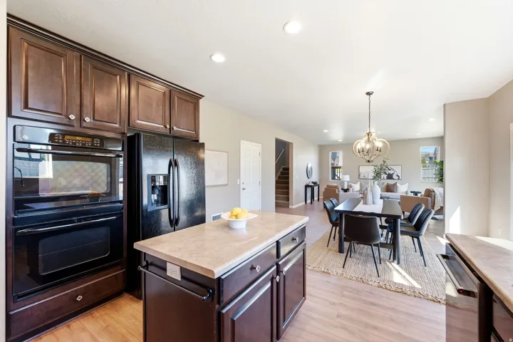 Kitchen featuring dark wood cabinetry, black built-in double ovens, and a kitchen island with integrated storage