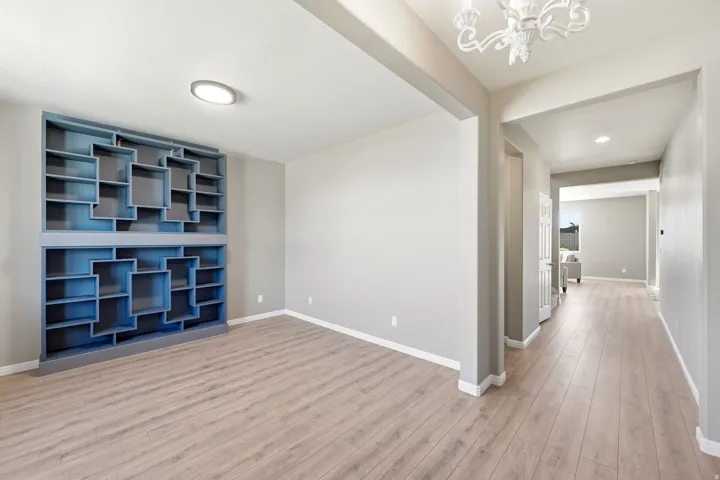 Built-in shelving unit, wood-finish flooring, recessed lighting, chandelier, and a bright interior