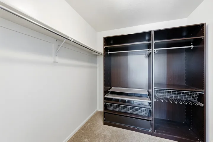 Custom closet system with dark wood-finish cabinetry, integrated metal drawers, and shelving
