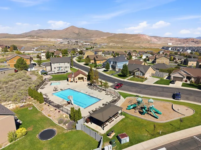 Community swimming pool, adjacent recreational play structure, covered outdoor seating area, manicured lawns, and surrounding residential properties