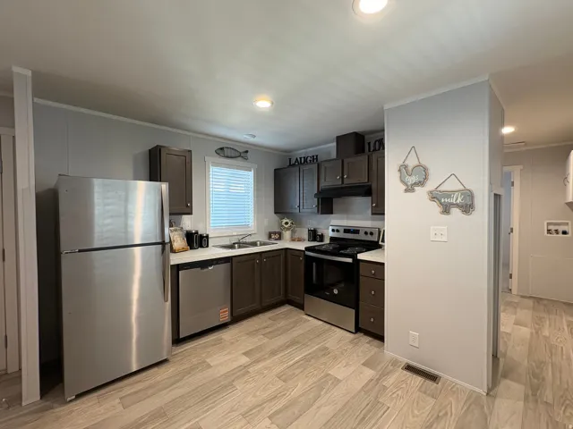 Kitchen featuring wood-finish flooring, stainless steel appliances, dark wood cabinetry, white countertops, and recessed lighting