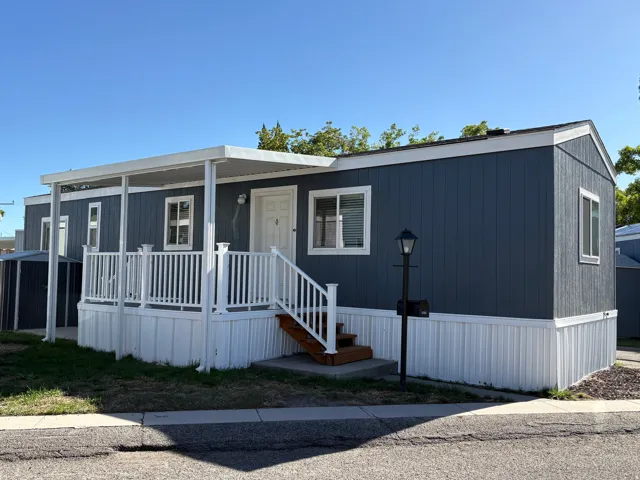 Front exterior featuring blue siding, white trim, covered porch, and white railings