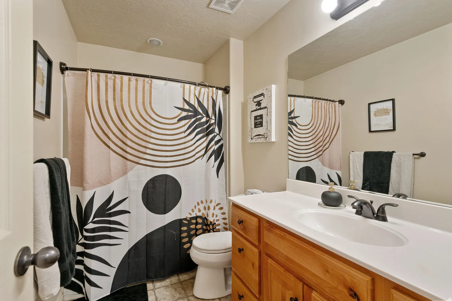 Bathroom featuring a wood-finish vanity with an integrated sink, a built-in wall mirror, and a toilet