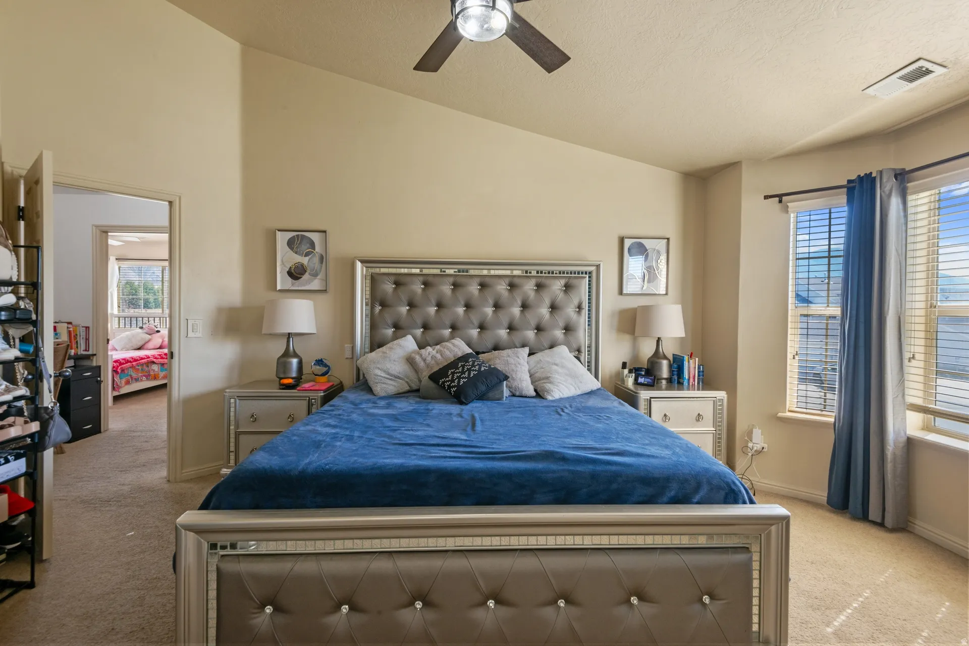 Vaulted ceiling with a ceiling fan, bay window with blinds, and neutral carpeting