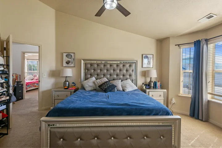 Vaulted ceiling with a ceiling fan, bay window with blinds, and neutral carpeting