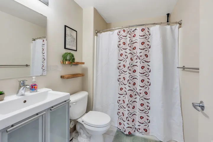 White vanity with integrated sink, chrome faucet, wall-mounted mirror, and floating wood shelves