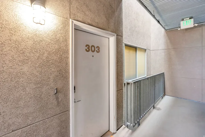Textured exterior wall finish, contemporary door, corrugated metal ceiling, and exterior window