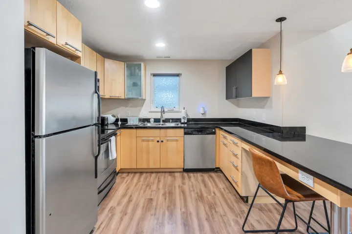 Kitchen featuring wood-finish flooring, dark countertops, stainless steel appliances, and pendant lighting