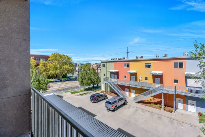 Paved parking area with concrete surface and a multi-level building exterior featuring diverse color panels
