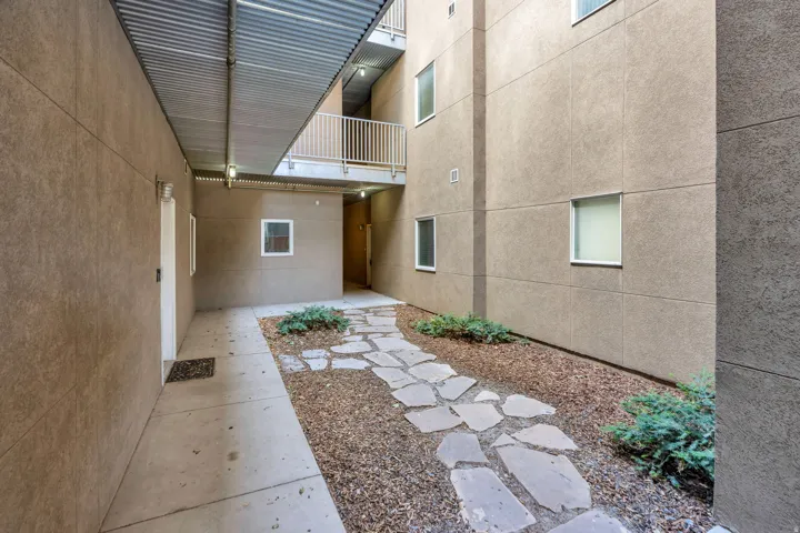 Concrete walkway leading to a stone paver path, surrounded by gravel and low-lying shrubs