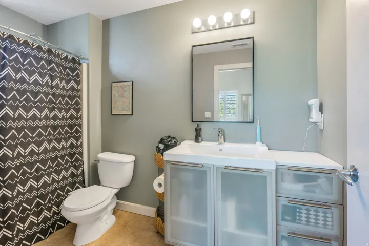 Vanity with integrated sink, wall-mounted mirror, and four-light fixture