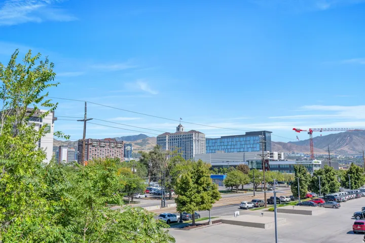 Expansive urban setting featuring diverse architectural styles, a street with parked vehicles, and distant mountain topography under a clear sky