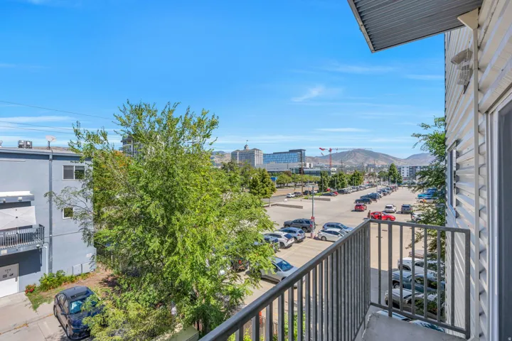 Balcony with metal railing, showcasing surrounding buildings and distant hills under a clear sky