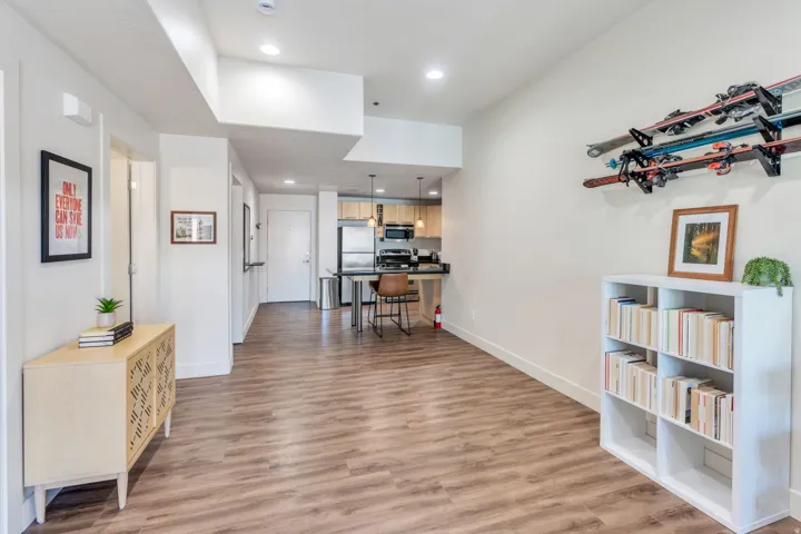 Wood-finish flooring throughout, recessed lighting, and a kitchen with stainless steel appliances, pendant lighting, and a breakfast bar