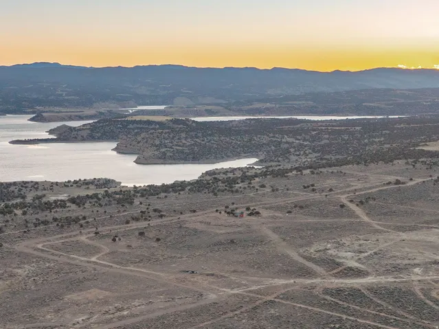 Expansive natural landscape featuring multiple bodies of water, distant mountain ranges, and scattered vegetation