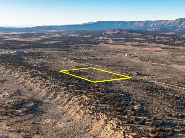 Expansive desert terrain with a marked rectangular property boundary, surrounded by natural shrubbery and distant mountainous formations